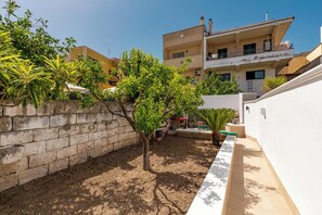 A courtyard with a tree, a small pool, and a white wall. - Casa Giselda by BarbarHouse (San Giorgio Ionico)