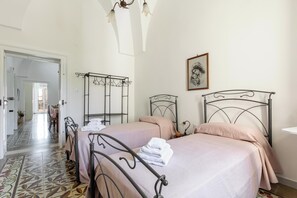 A bedroom with two beds, a metal headboard, a hanging light fixture, and a framed picture on the wall. - Casa Giselda by BarbarHouse (San Giorgio Ionico)