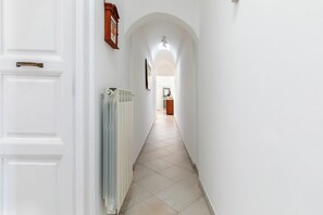 A hallway with white walls, a radiator, and a door with a handle. - Casa Giselda by BarbarHouse (San Giorgio Ionico)