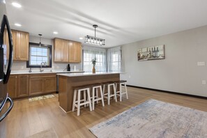 A modern kitchen with wooden cabinets, a central island with stools, and a large window with curtains. - 6 Bedroom/3 Bathrooms, 6 Acres Country House (Aberdeen)