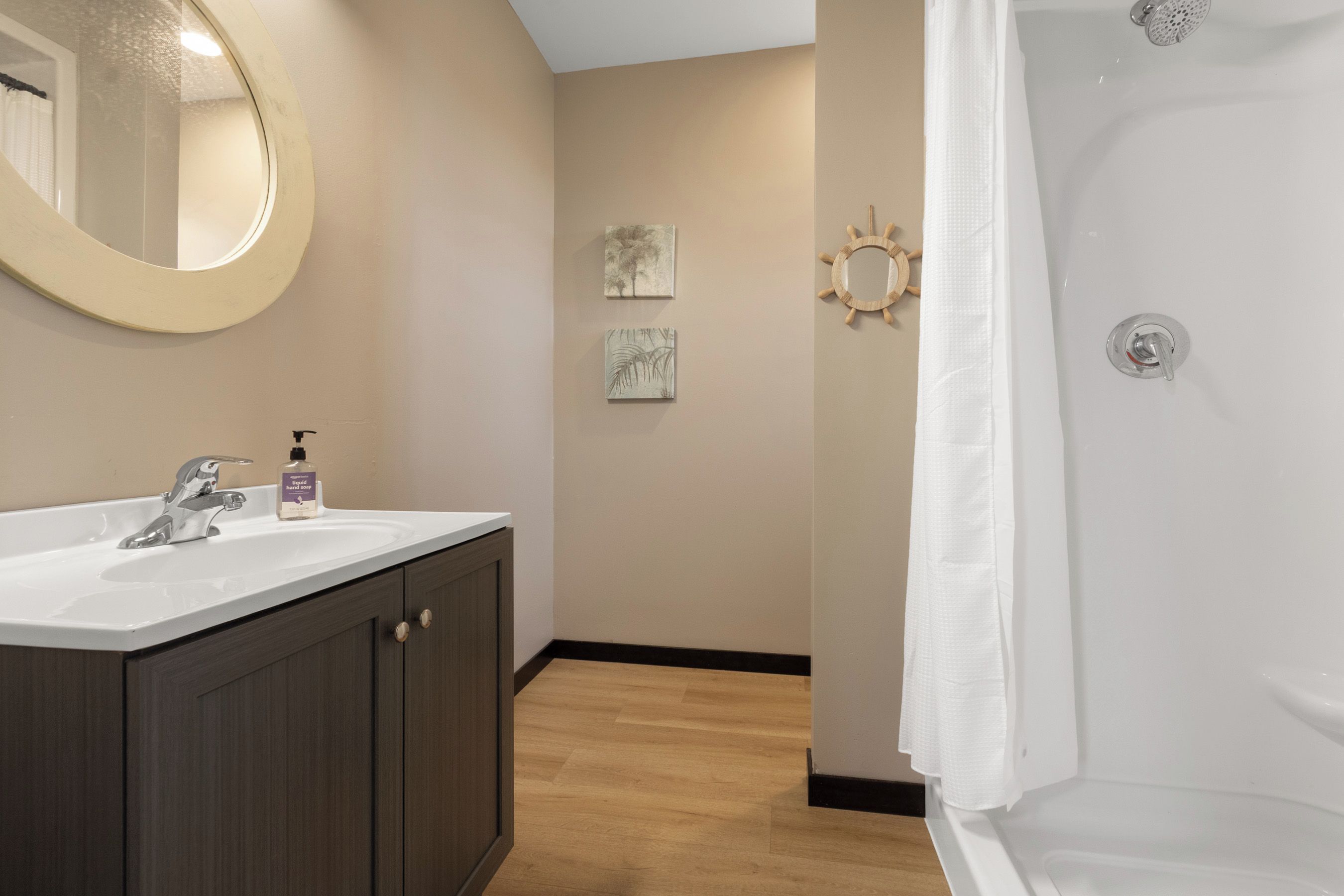 A bathroom with a sink, mirror, and shower.