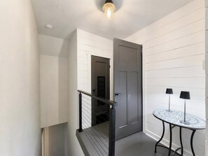 A modern interior with a staircase, a door, and a small table with two lamps. - Fountain Square 3BR Sleeps 6 Near Downtown (Indianapolis)