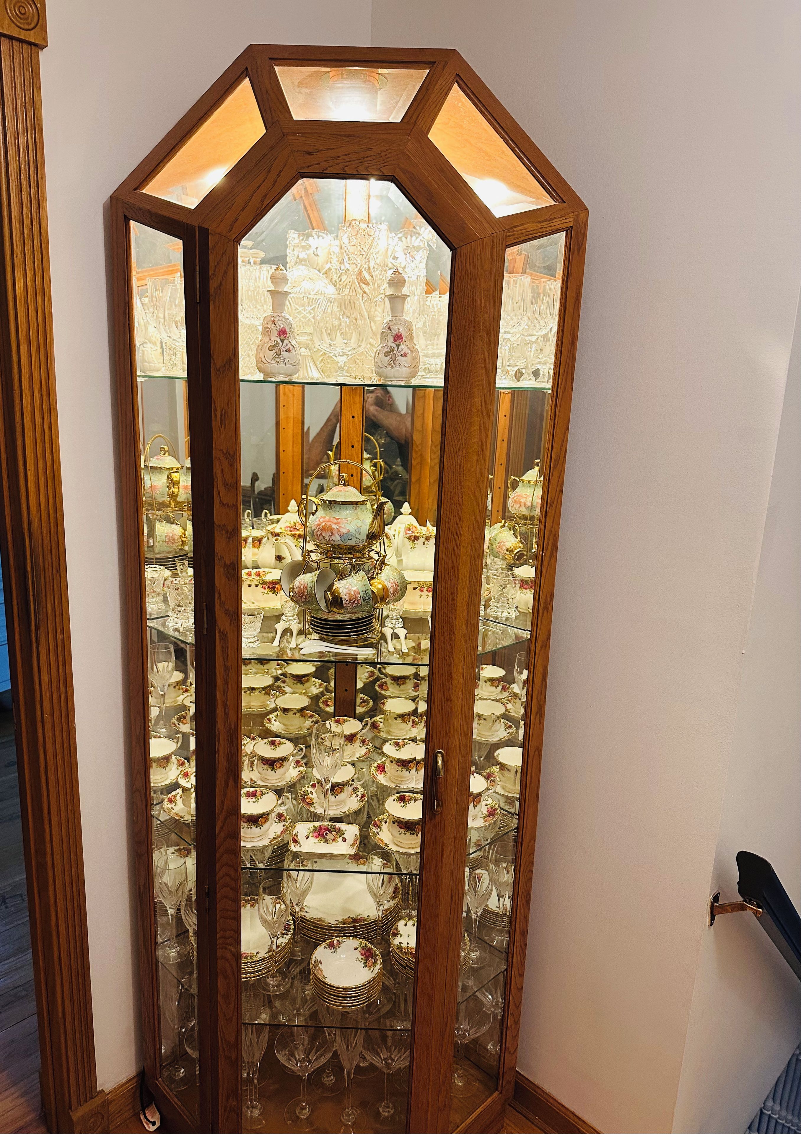A wooden display cabinet with glass doors containing various glassware and porcelain items.
