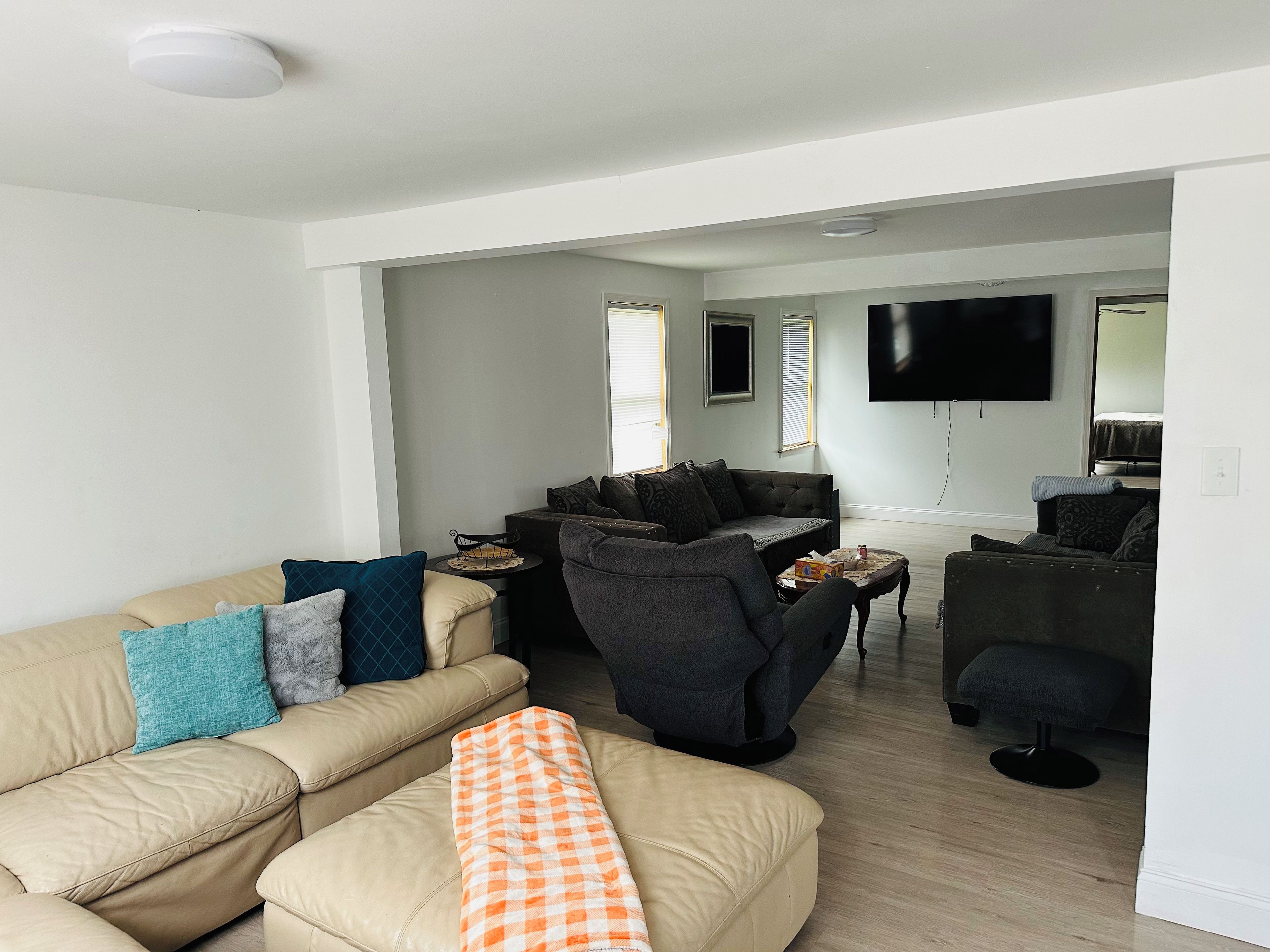 Een moderne woonkamer met een beige bank, een grijze fauteuil en een salontafel.