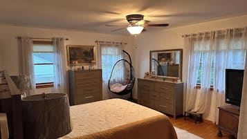 A bedroom with a bed, dresser, vanity, and a ceiling fan.