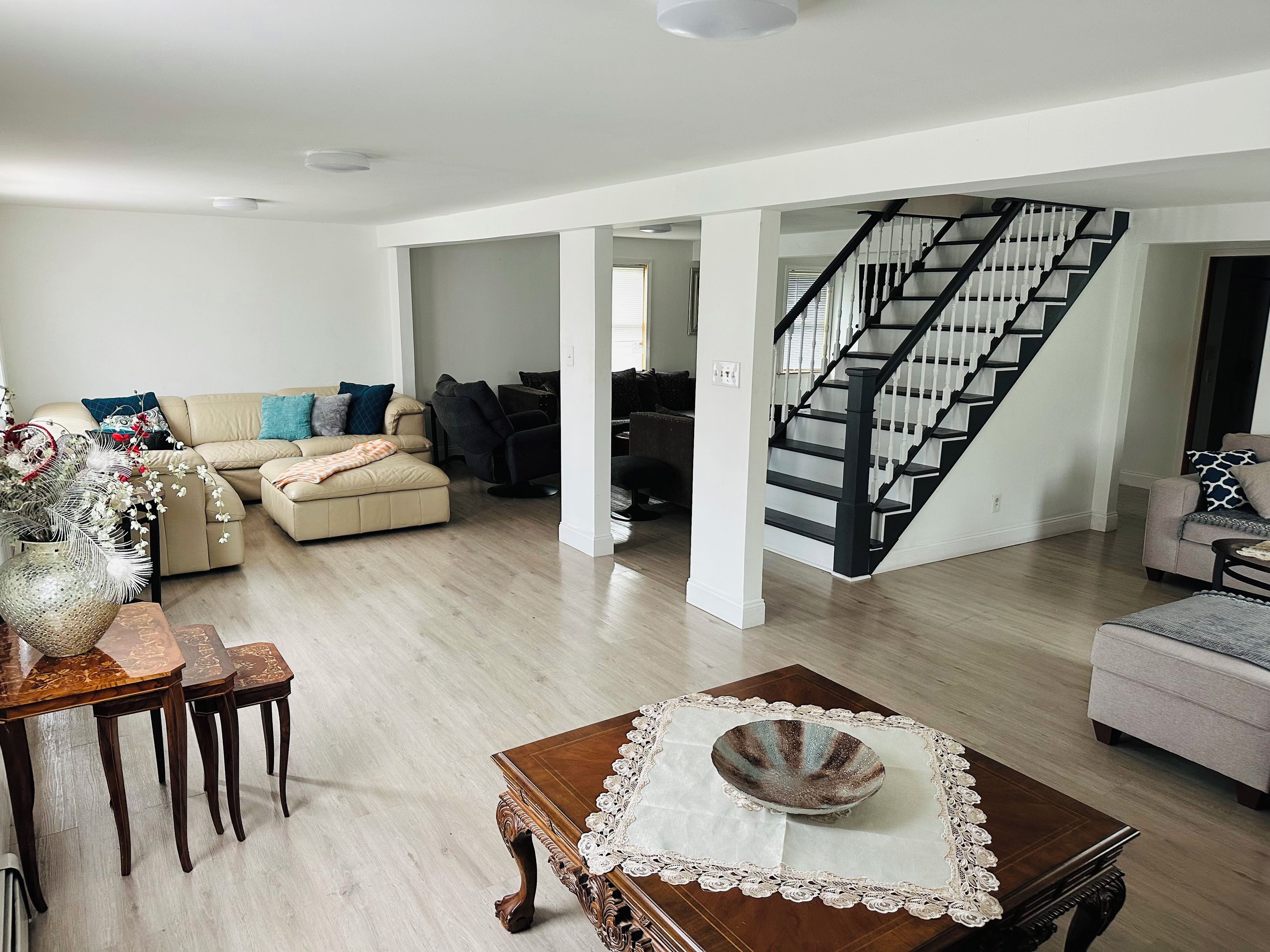 A spacious living area with a staircase, a dining table with chairs, and a sofa set.