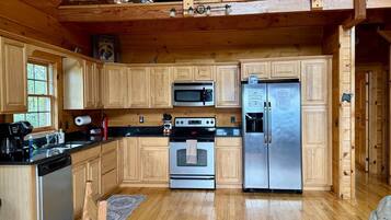 Een houten cabinestijl interieur met een keuken, inclusief een magnetron, oven en koelkast.