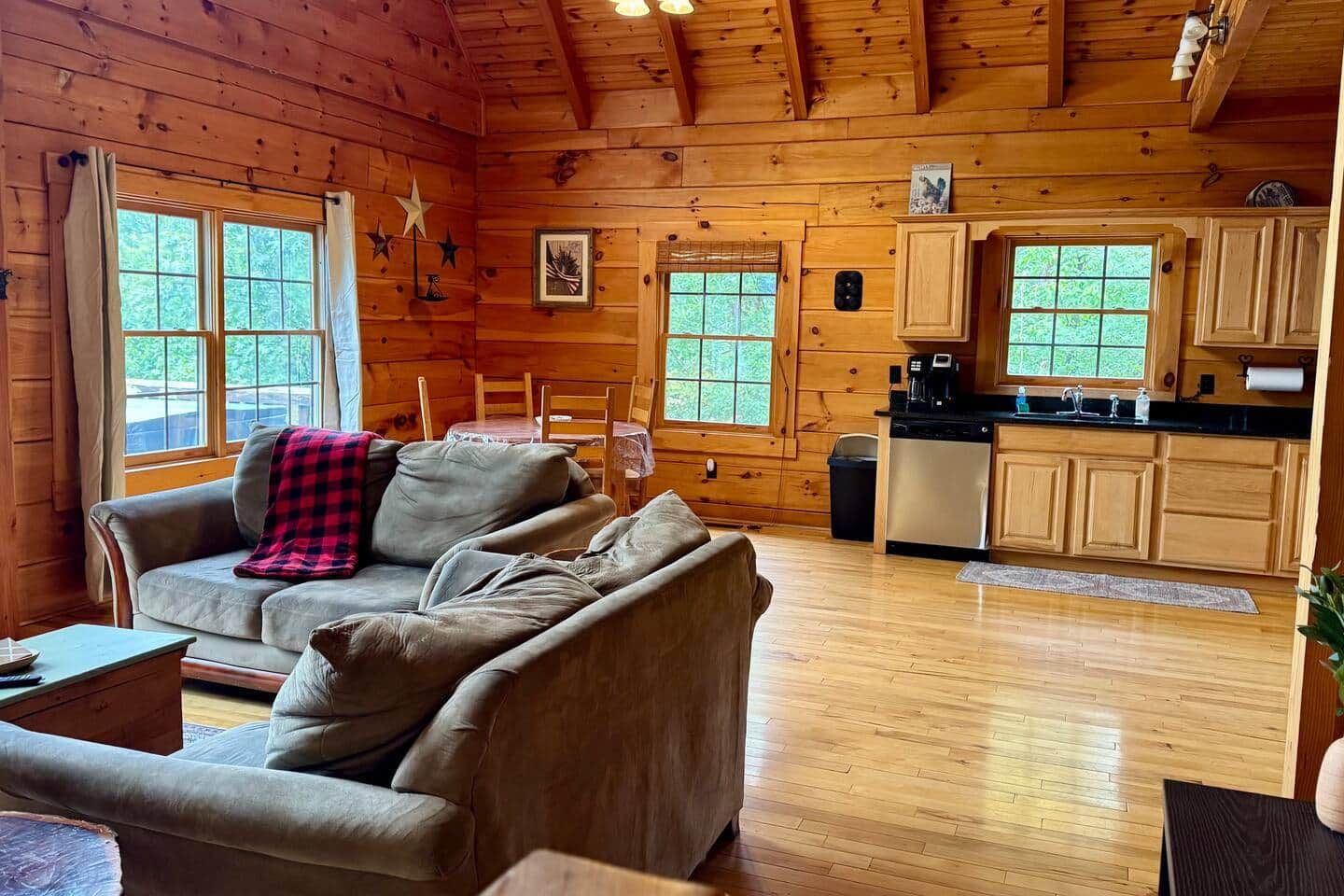 Een gezellig chalet binnen met een bank, eettafel en keukenhoek.
