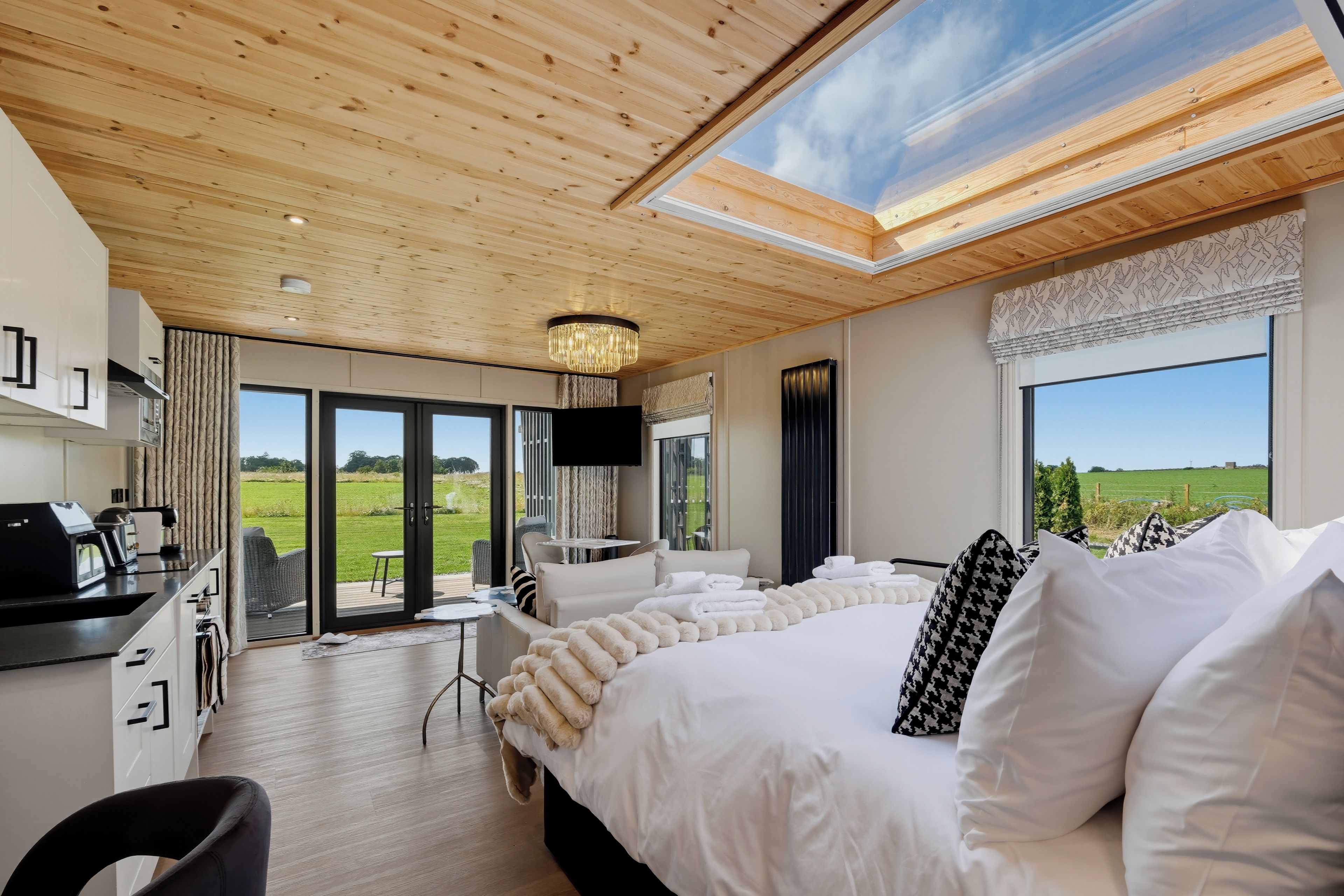 A modern bedroom with a large bed, a desk, and a view of the outdoors.
