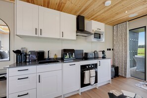 A modern kitchen with white cabinets, a built-in oven, and a microwave. - Luxury Lodge Milano with Hot Tub at Pitcaple Lodge Retreats, Aberdeenshire (Pitcaple)