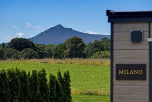 A building with a sign that reads 'MILANO' in front of a grassy field with a mountain in the background. - Luxury Lodge Milano with Hot Tub at Pitcaple Lodge Retreats, Aberdeenshire (Pitcaple)