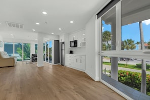 A modern kitchen with white cabinets, a stainless steel refrigerator, and a flat-screen TV.