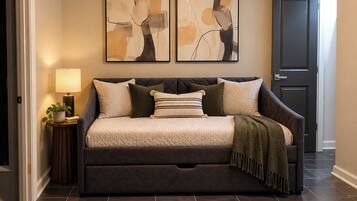 A room with a dark-colored sofa, a patterned rug, abstract wall art, a ceiling fan, and a door.