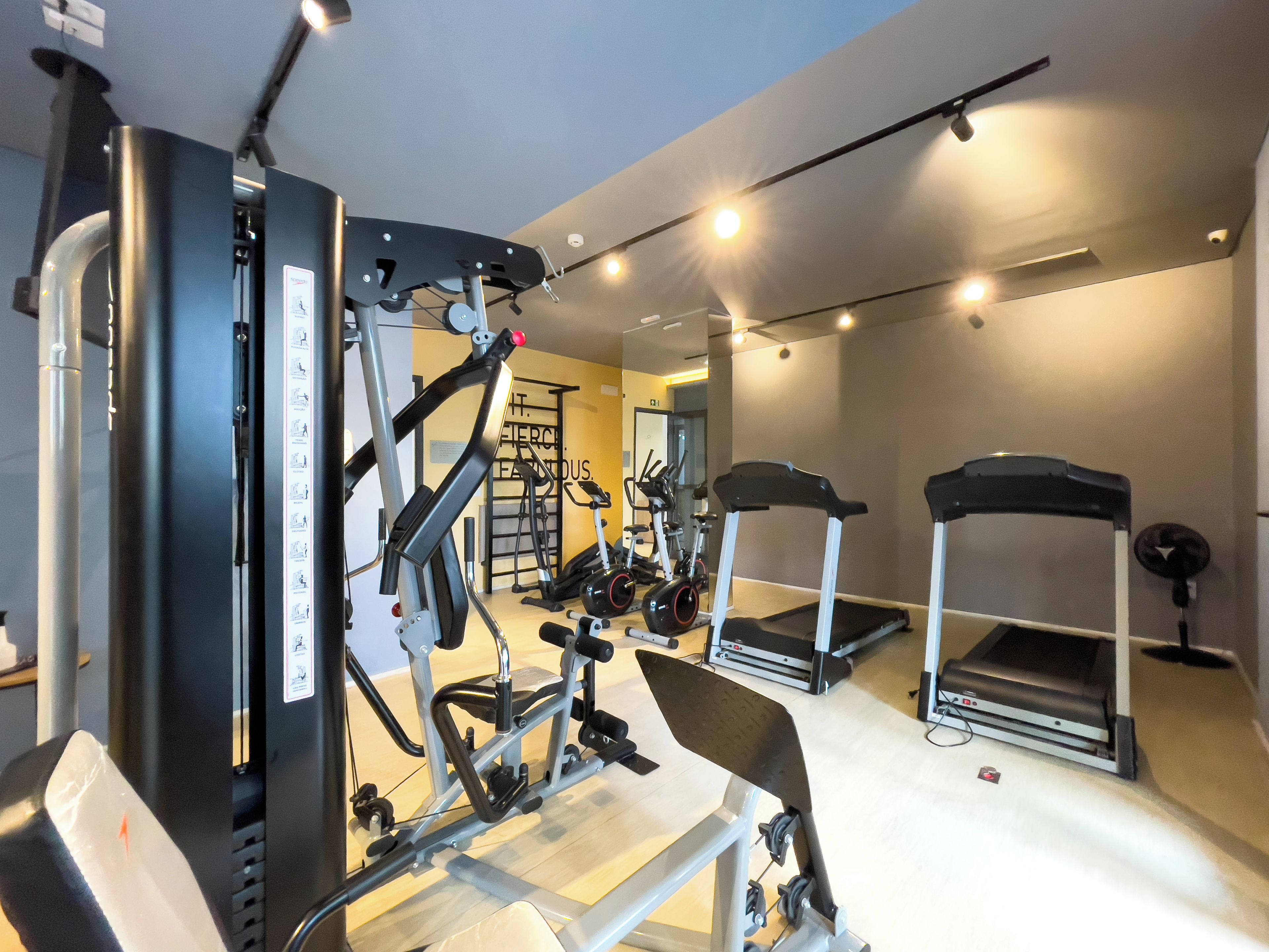 Un gimnasio con equipo de ejercicio, cintas de correr y un espejo.