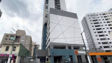 A modern building with a prominent glass facade, a visible entrance, and a parking area with a sign indicating the number 117.