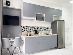 Una cocina moderna con armarios grises, un refrigerador de acero inoxidable, un microondas y un salpicadero de azulejos.