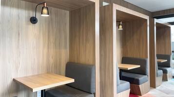 A modern interior with wooden panel walls, built-in seating with attached tables, and pendant lighting.