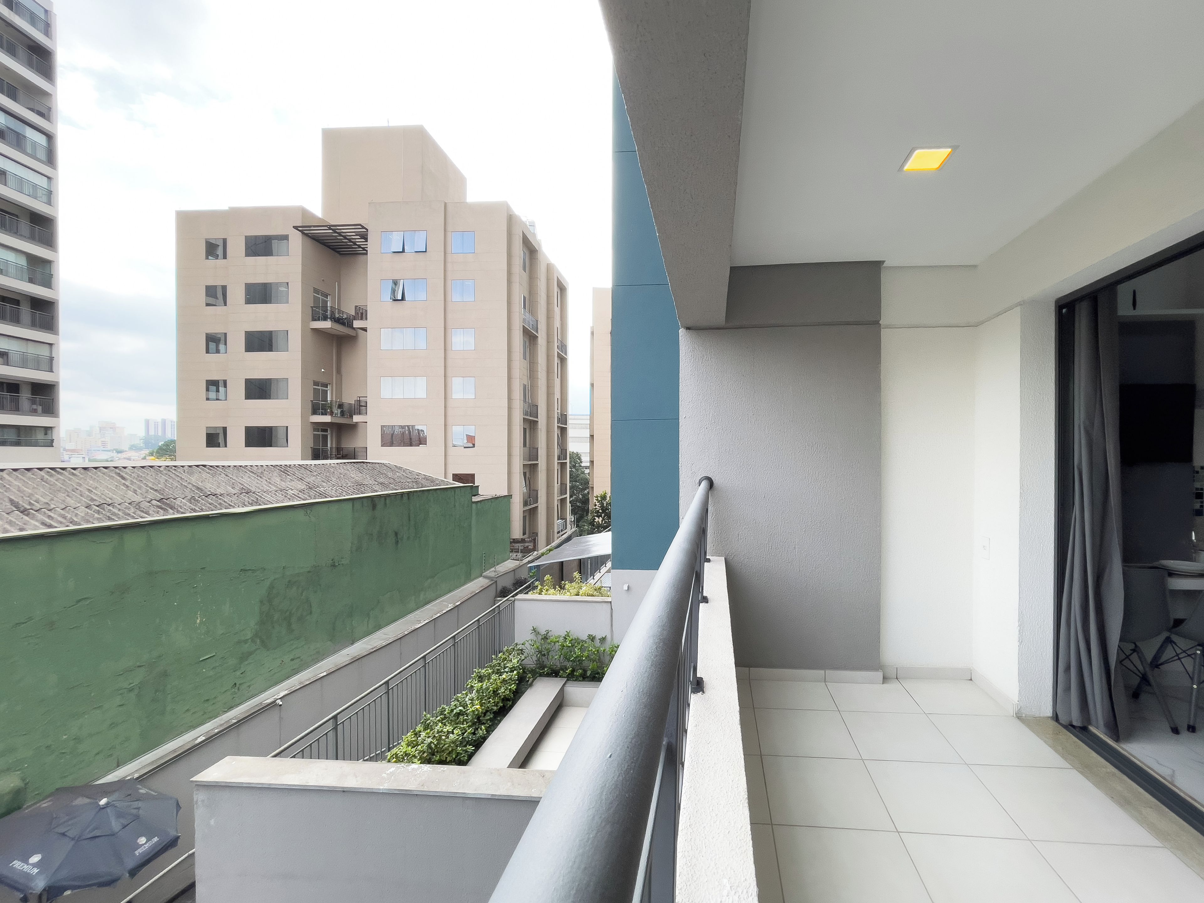 A balcony with a metal railing, a green wall, and a view of adjacent buildings.