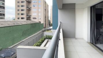 A balcony with a metal railing, a green wall, and a view of adjacent buildings.