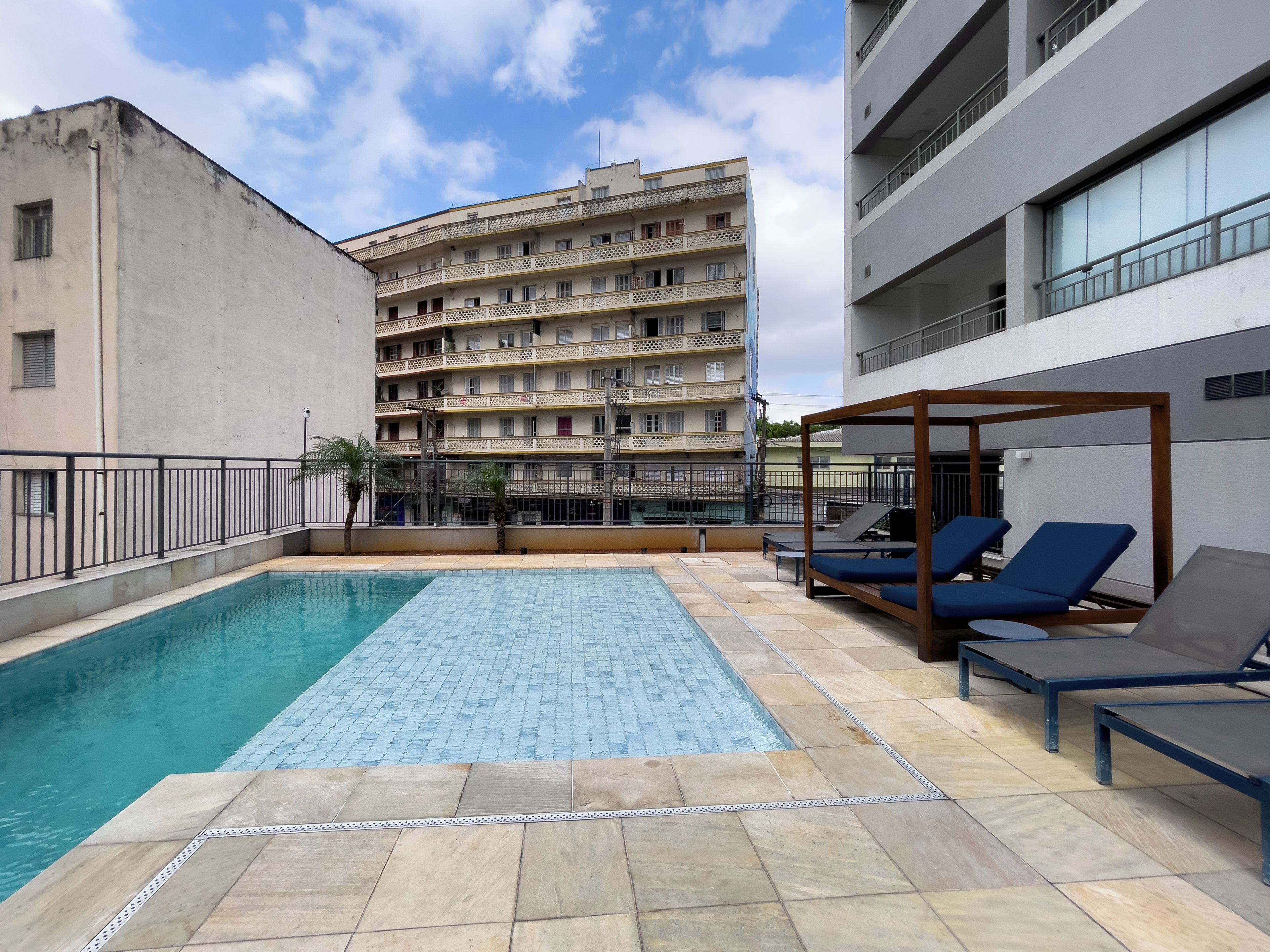 A rooftop pool area with lounge chairs and a building in the background.