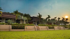 Un hotel de estilo arquitectónico tradicional, con un patio que cuenta con palmeras y un césped bien cuidado.