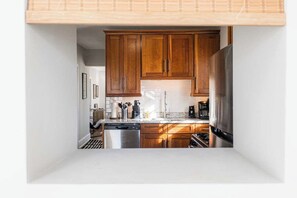A kitchen with wooden cabinets, stainless steel appliances, and a white countertop. - Artsy Chicago Stay with Patio, Parking & Sleeps 7 (Chicago)