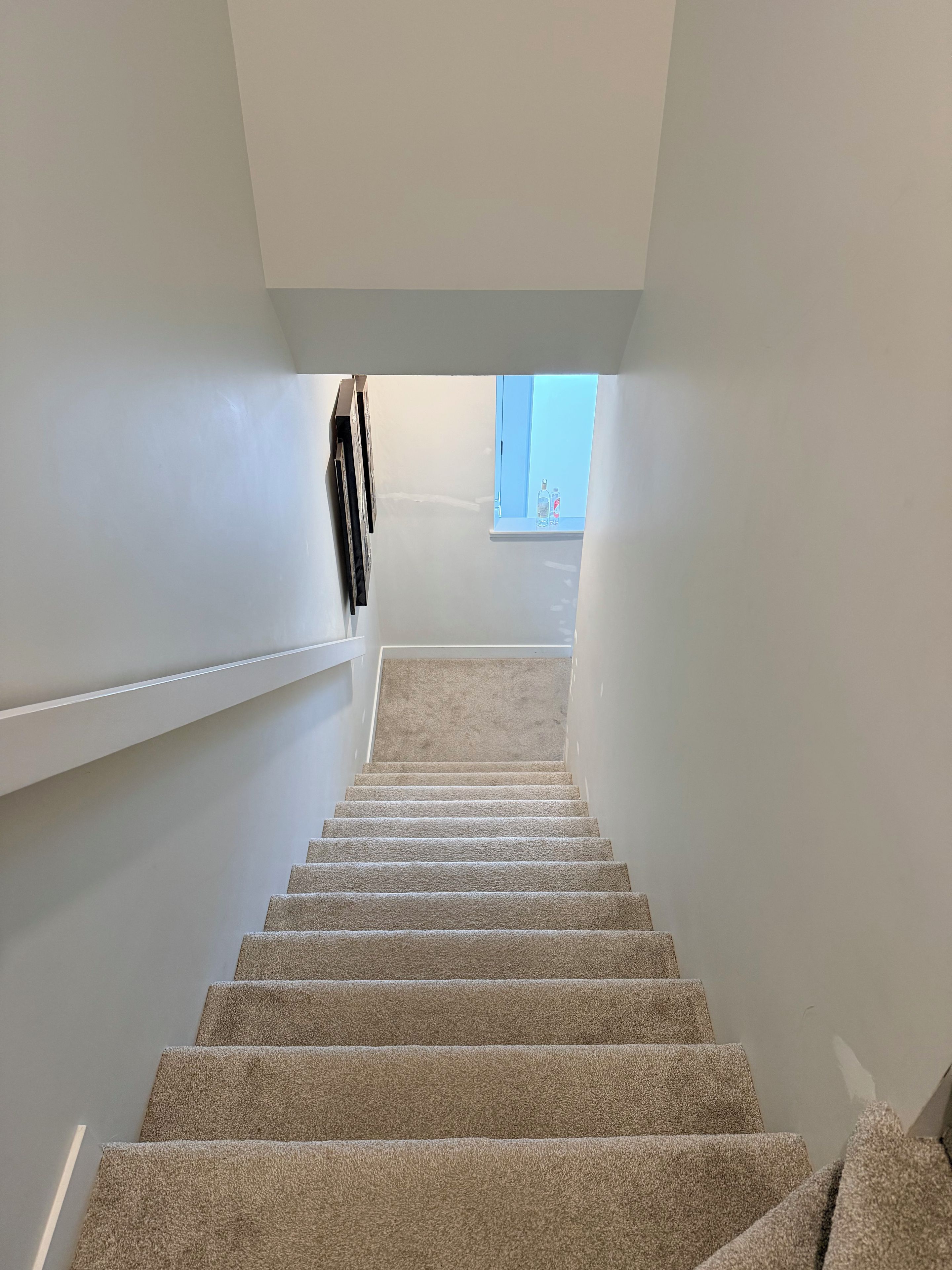 A carpeted staircase leading to a window with a view.
