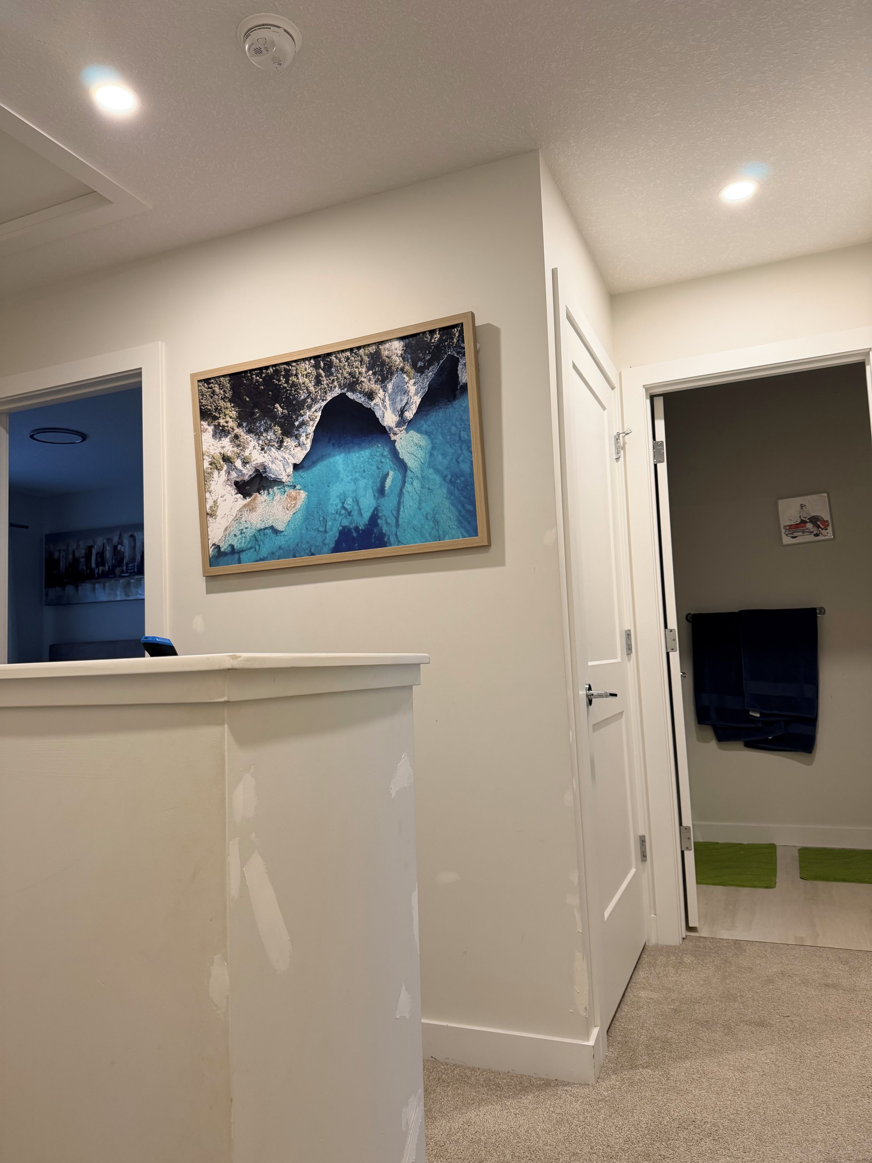 Un'area di accoglienza con un quadro raffigurante una scena costiera, una porta chiusa e un oggetto blu su un bancone.
