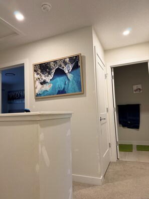A reception area with a painting of a coastal scene, a closed door, and a blue object on a counter. - Ubbies place 1-Entire 4-Bed House - Private - Sleeps 8 - Regina (Regina)