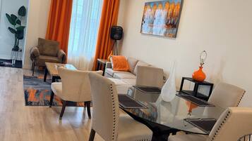 Un salon moderne avec un coin repas, comprenant une table en verre, des fauteuils en cuir et un tableau accroché au mur.
