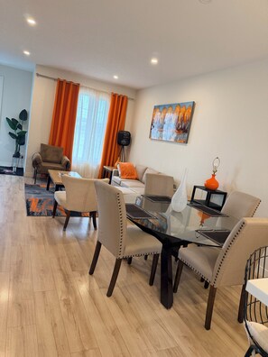 A modern living room with a dining area, featuring a glass table, leather chairs, and a painting on the wall. - Ubbies place 1-Entire 4-Bed House - Private - Sleeps 8 - Regina (Regina)
