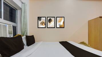 Una habitación de hotel con una cama, una ventana y tres cuadros en la pared.