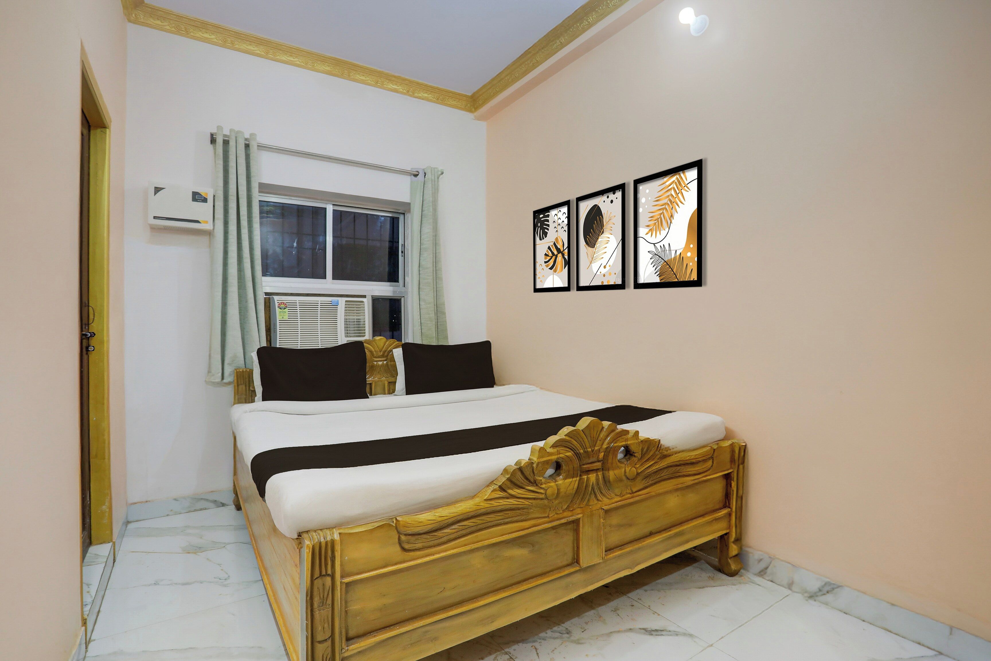 Un dormitorio con cama, ventana con cortinas, unidad de aire acondicionado y cuadros en la pared.