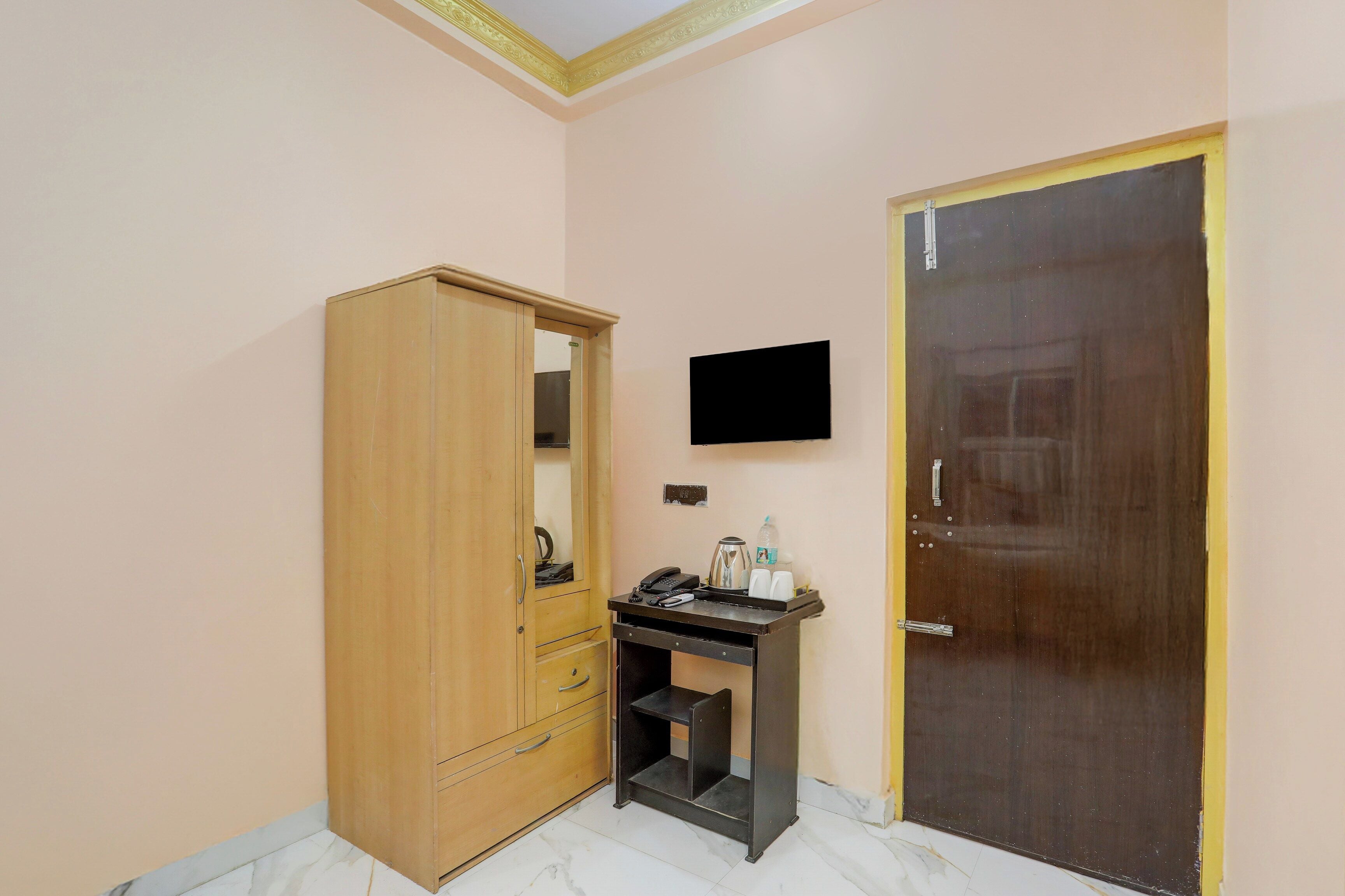 Una habitación con un armario de madera, un escritorio con televisor de pantalla plana y una puerta cerrada.