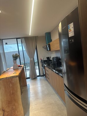 A modern kitchen with a stainless steel refrigerator, wooden cabinets, and a built-in microwave. - New Listing (São Miguel dos Milagres)