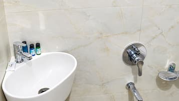 Un baño con lavamanos blanco, grifos cromados y pared de mármol.