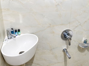 A bathroom with a white sink, chrome faucets, and a marble wall. - Hotel Utsav (Maheshwar)