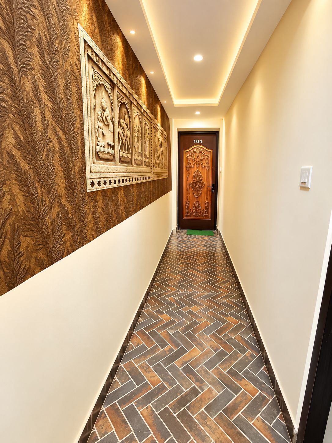 Un pasillo con paredes estampadas, piso de espiga y una puerta con el número 104.