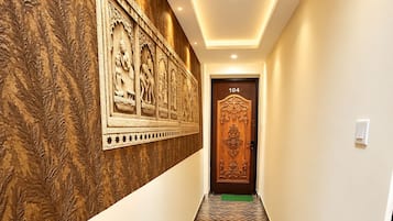 Un pasillo con paredes estampadas, piso de espiga y una puerta con el número 104.