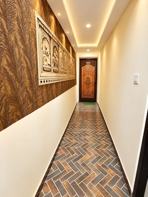 A hallway with patterned walls, a herringbone floor, and a door with the number 104. - Hotel Utsav (Maheshwar)
