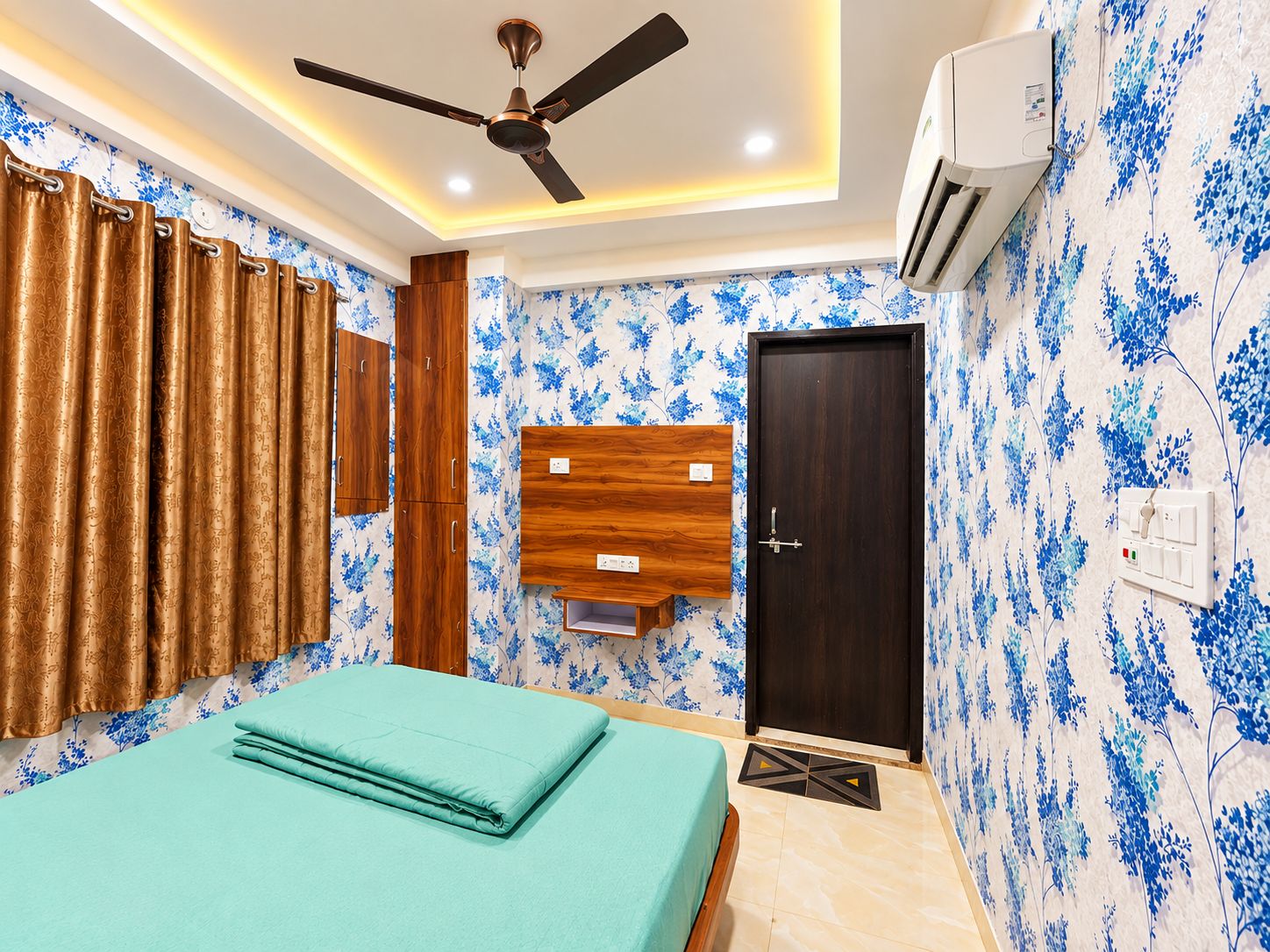 Un dormitorio con cama, ventilador de techo, equipo de aire acondicionado, armario de madera y una puerta.