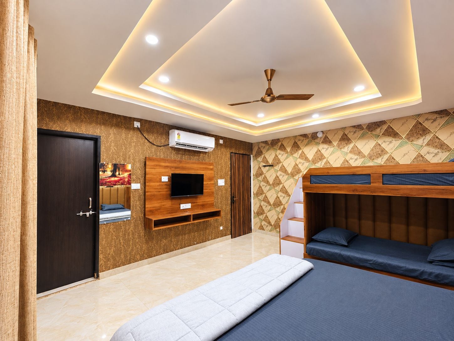 Un dormitorio con cama, televisor montado en un panel de madera, ventilador de techo y pared con diseño.