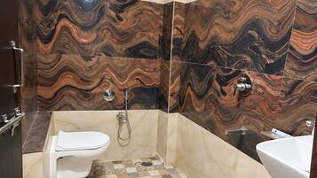 Un baño con tocador de mármol, ducha e inodoro.