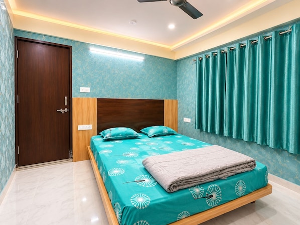 A bedroom with a bed, a ceiling fan, and a window with curtains. - Hotel Utsav (Maheshwar)