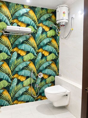 A bathroom with a toilet, a shower, and a water heater mounted on the wall. - Hotel Utsav (Maheshwar)