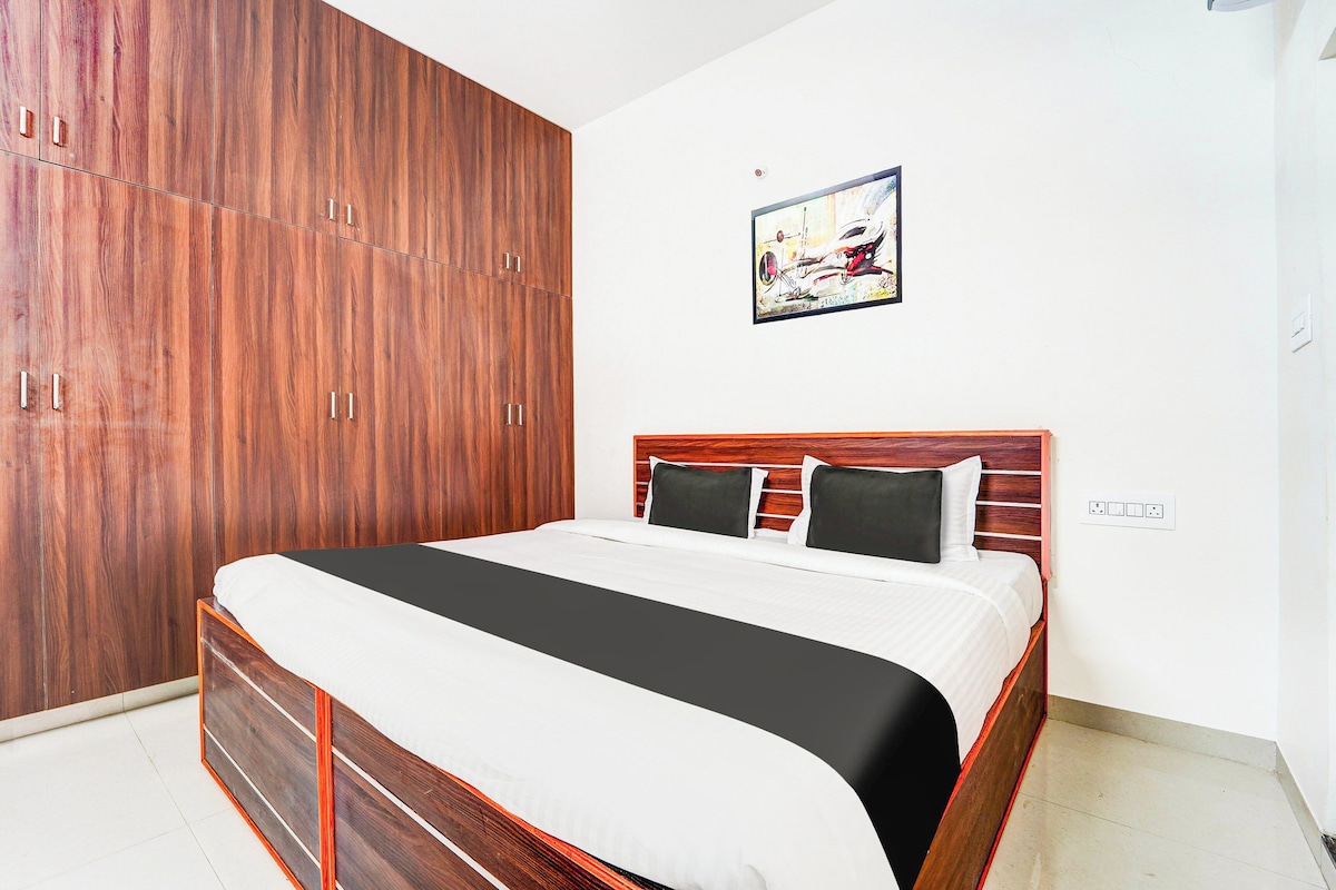 Un dormitorio con un amplio armario de madera, una cama con colcha blanco y negro, y un cuadro en la pared.