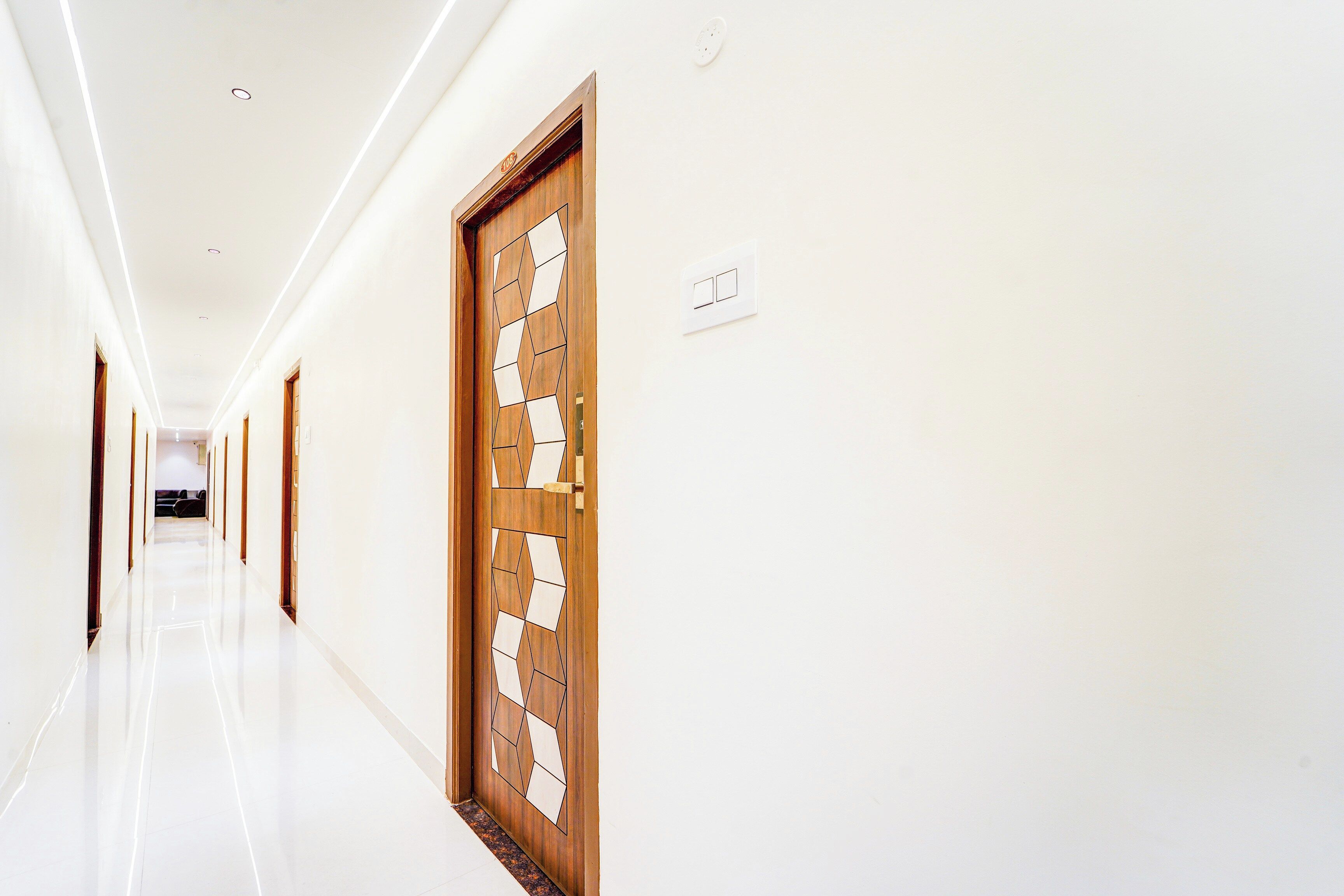 A long, well-lit hallway with a wooden door featuring a geometric pattern.