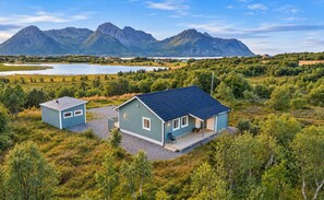 A two-story house with a dark roof, a porch, and a view of mountains and a lake. - Fabulous 2-bedroom estate in charming Nordland perfect for relaxing getaway (Nordland)