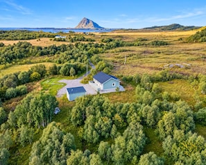 A single-story house with a sloped roof, surrounded by dense greenery and a clear sky. - Fabulous 2-bedroom estate in charming Nordland perfect for relaxing getaway (Nordland)