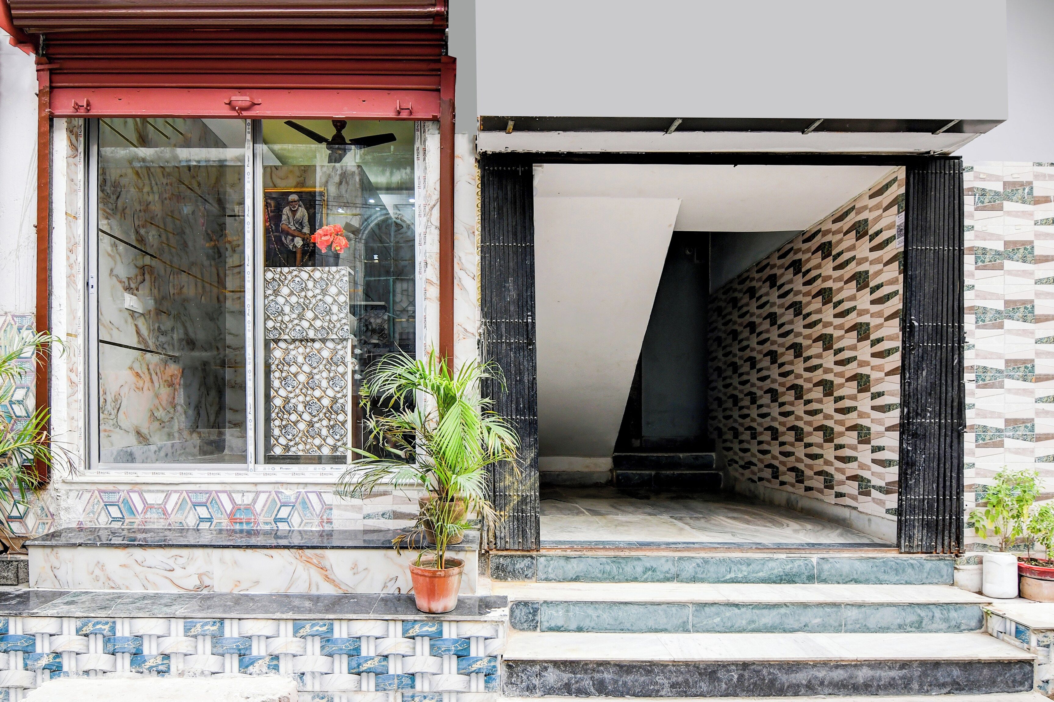 A building entrance with a red awning, a glass door, and a patterned wall.